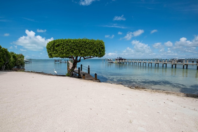 view of dock with a beach view and a water view