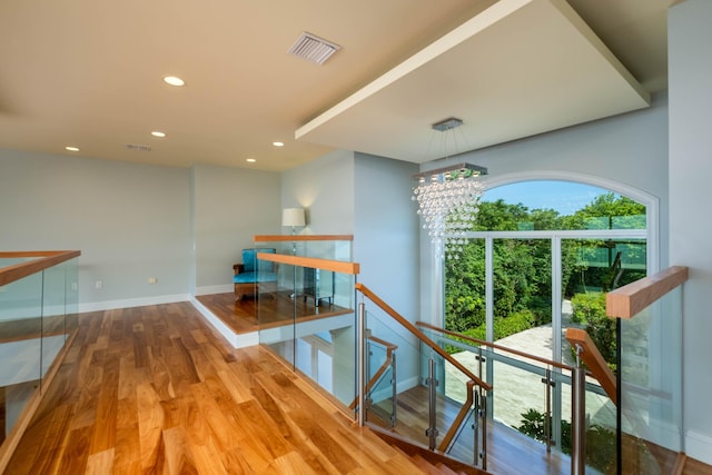 hallway with hardwood / wood-style flooring and an inviting chandelier