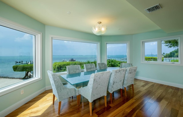 dining area with wood-type flooring and a water view