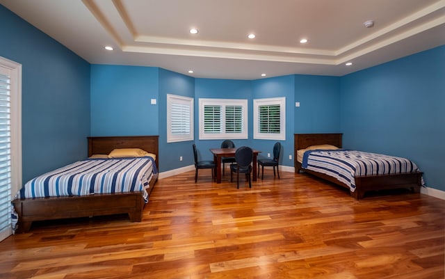 bedroom with a tray ceiling and light hardwood / wood-style floors