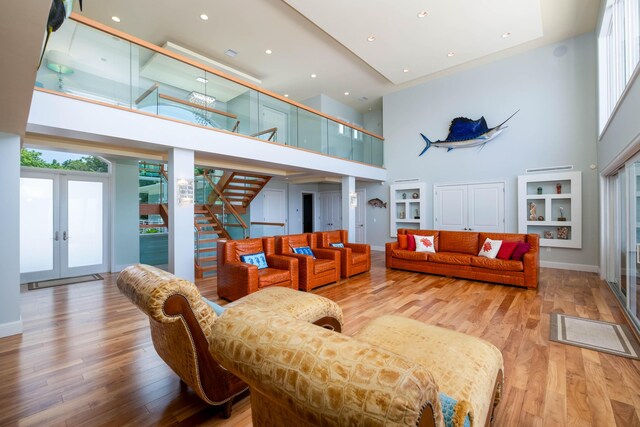 living room featuring a towering ceiling, light hardwood / wood-style flooring, and french doors