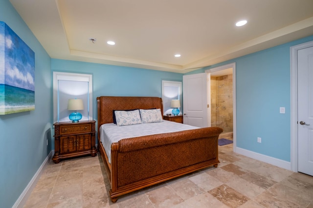 bedroom with ensuite bathroom and a tray ceiling