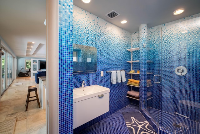 bathroom with sink, tile patterned flooring, a shower with door, and tile walls