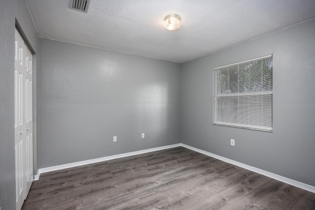 empty room featuring baseboards, visible vents, and dark wood-style flooring