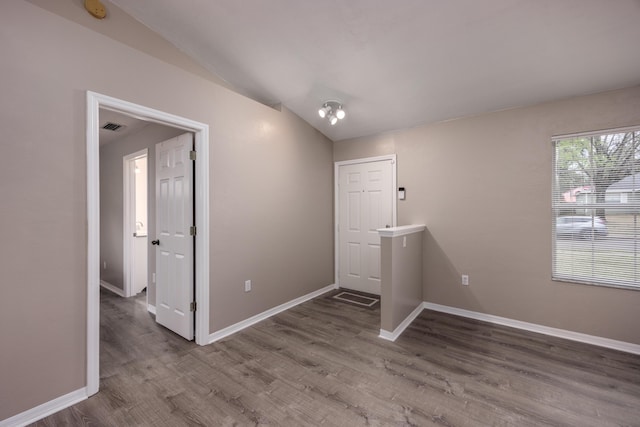 interior space featuring baseboards, visible vents, vaulted ceiling, and wood finished floors