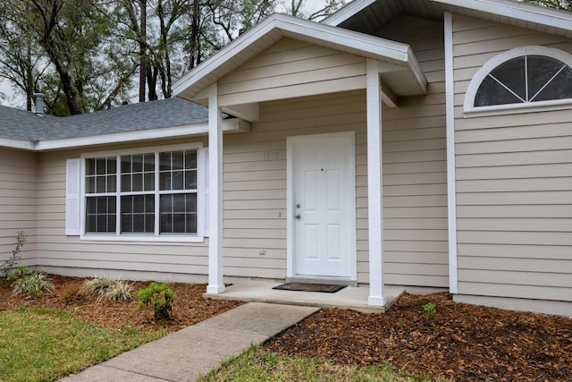 doorway to property with roof with shingles