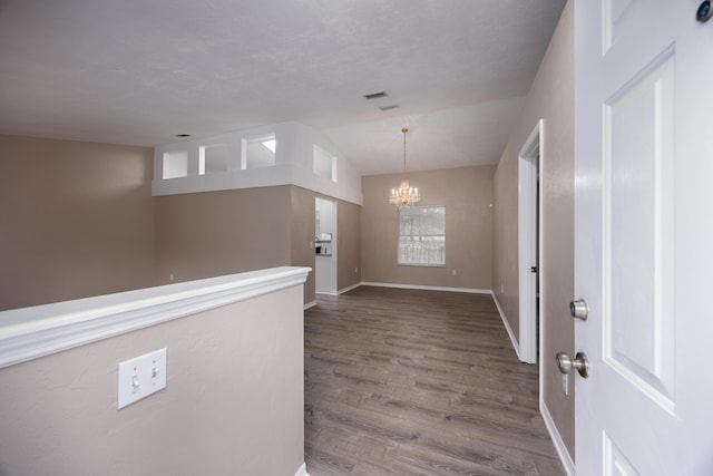 foyer featuring vaulted ceiling, a notable chandelier, baseboards, and wood finished floors