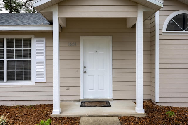 entrance to property featuring roof with shingles