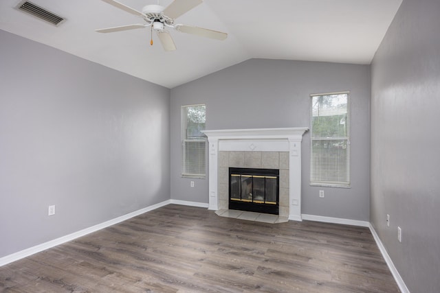 unfurnished living room with a healthy amount of sunlight, visible vents, a tiled fireplace, and wood finished floors