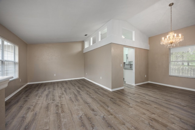 unfurnished room featuring visible vents, baseboards, lofted ceiling, wood finished floors, and a notable chandelier