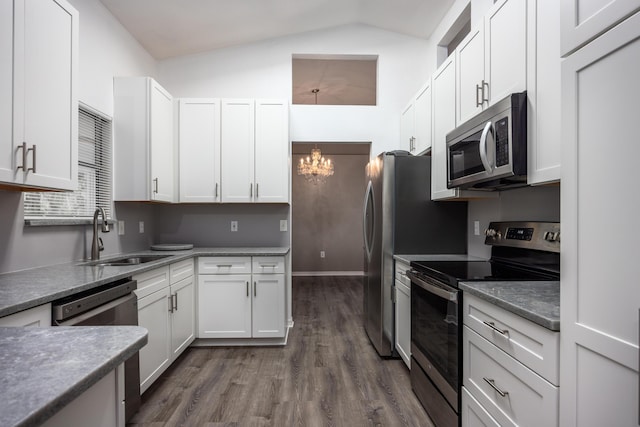 kitchen with dark wood finished floors, a chandelier, stainless steel appliances, white cabinetry, and a sink