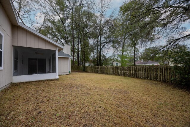 view of yard with a sunroom, a fenced backyard, and a ceiling fan