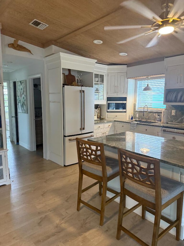 1672 Pandorea Ln, Big Pine, FL 33043 - kitchen featuring freestanding refrigerator, stainless steel microwave, white cabinetry, light wood-type flooring, and recessed lighting