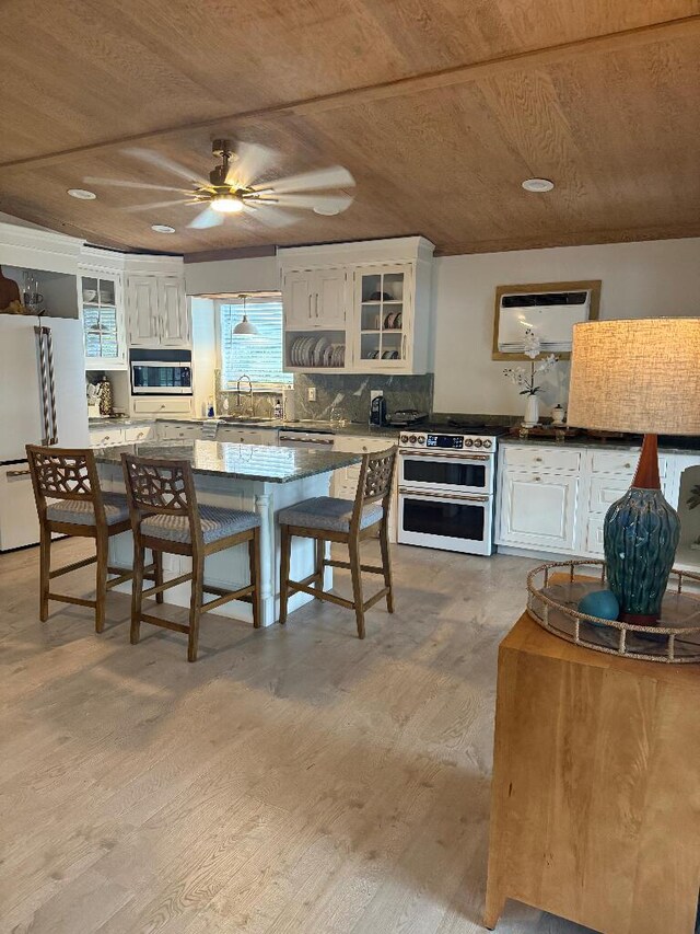 1672 Pandorea Ln, Big Pine, FL 33043 - kitchen with range with two ovens, freestanding refrigerator, light wood-style flooring, white cabinetry, and glass insert cabinets