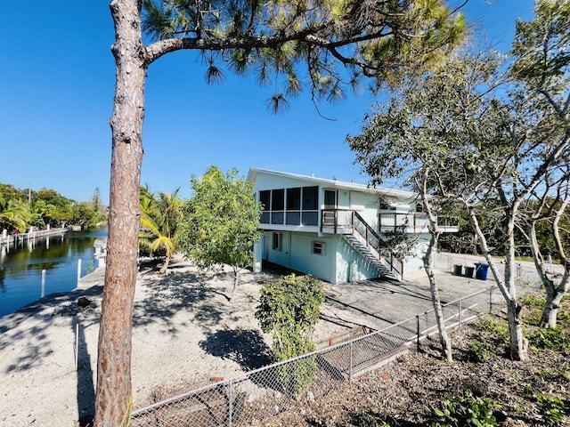 rear view of property with a sunroom and a water view