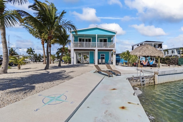 back of property with a gazebo, a balcony, and a water view