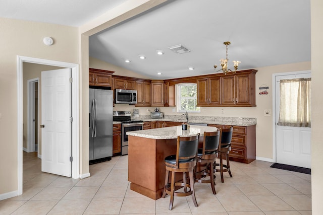 kitchen featuring lofted ceiling, light tile patterned floors, pendant lighting, stainless steel appliances, and a kitchen island