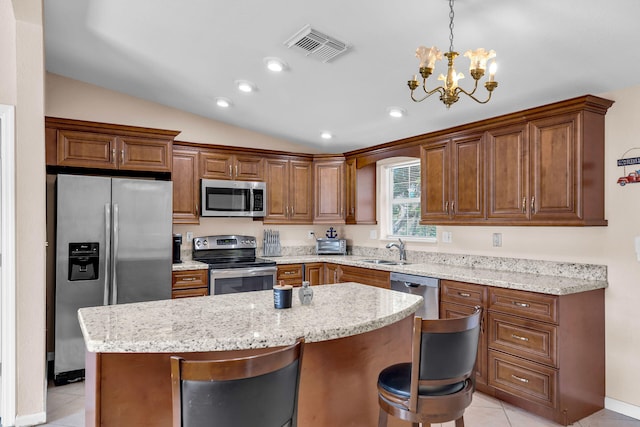 kitchen with pendant lighting, stainless steel appliances, a kitchen breakfast bar, and a center island