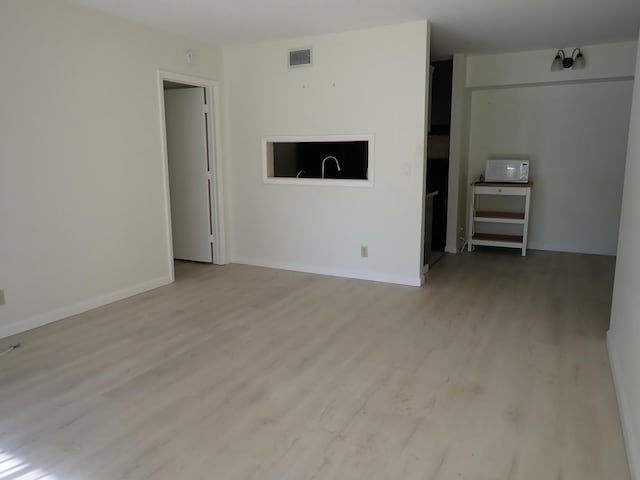 unfurnished living room featuring wood finished floors, visible vents, and baseboards