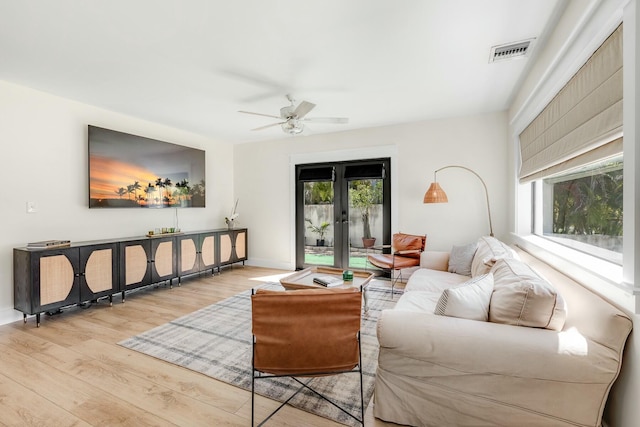 living room featuring visible vents, baseboards, a ceiling fan, french doors, and light wood finished floors