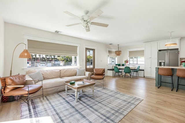 living room featuring visible vents, a wealth of natural light, light wood-style flooring, and a ceiling fan