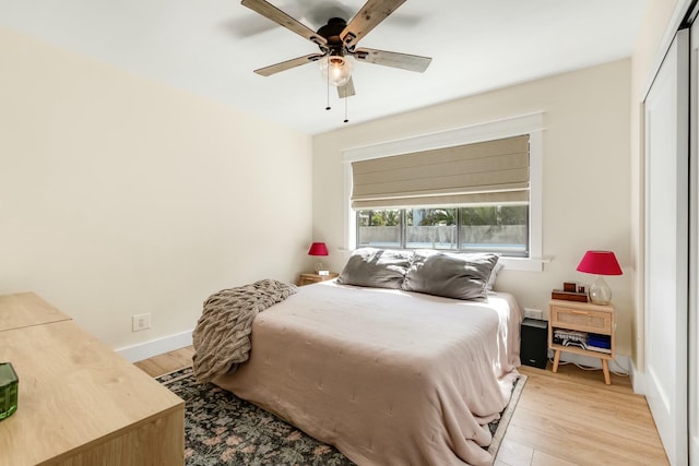 bedroom featuring ceiling fan, light wood-style flooring, and baseboards