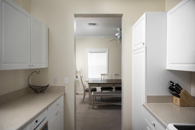 kitchen featuring dishwasher, white cabinets, ornamental molding, carpet, and ceiling fan