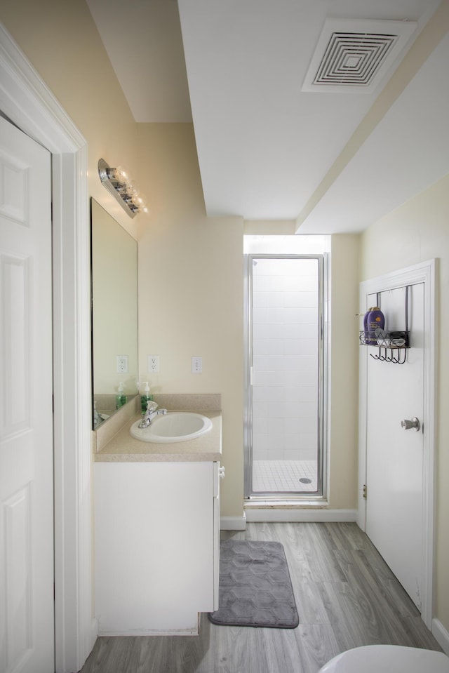 bathroom with vanity, a shower with shower door, and wood-type flooring