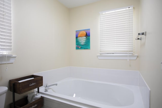 bathroom featuring tiled bath and toilet