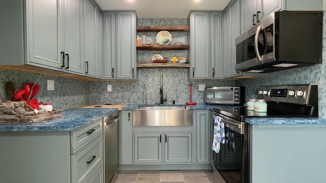 kitchen with appliances with stainless steel finishes, sink, decorative backsplash, and gray cabinetry