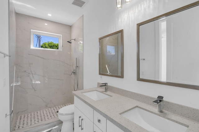 bathroom with vanity, a tile shower, and toilet