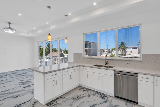 kitchen with pendant lighting, sink, white cabinetry, stainless steel dishwasher, and kitchen peninsula