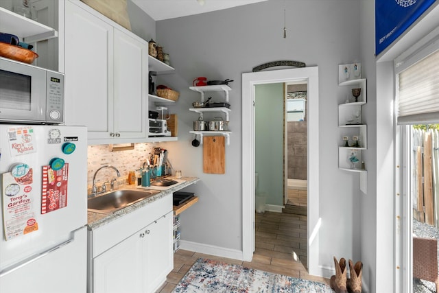 kitchen featuring sink, backsplash, white cabinets, and white appliances