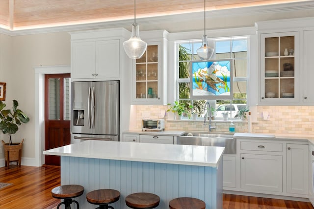 kitchen featuring sink, a breakfast bar, white cabinetry, stainless steel refrigerator with ice dispenser, and decorative light fixtures