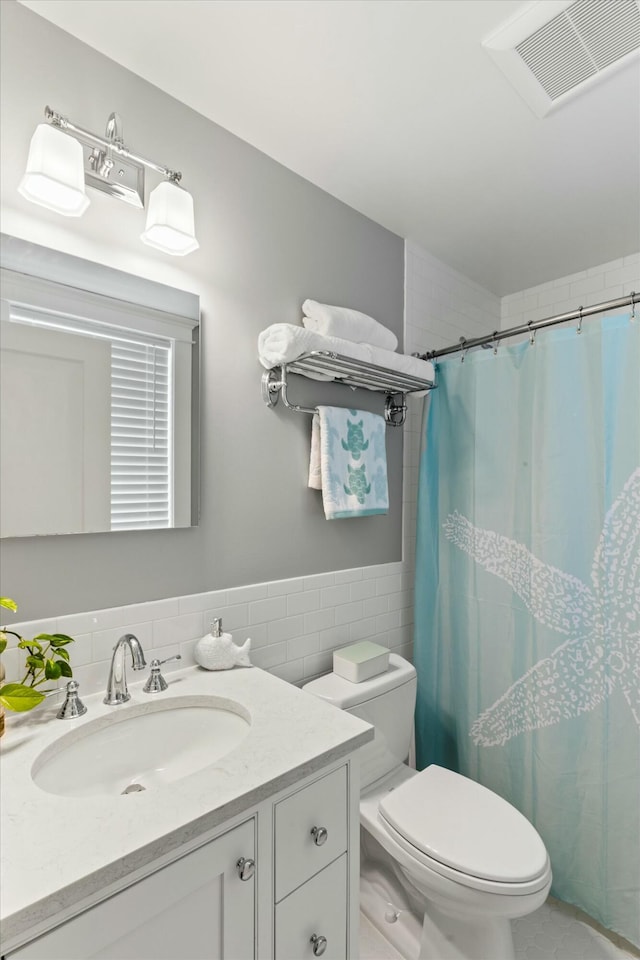 bathroom featuring tile walls, vanity, toilet, and walk in shower