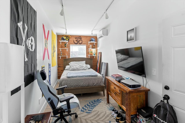 bedroom featuring an AC wall unit, light hardwood / wood-style flooring, rail lighting, and wooden walls