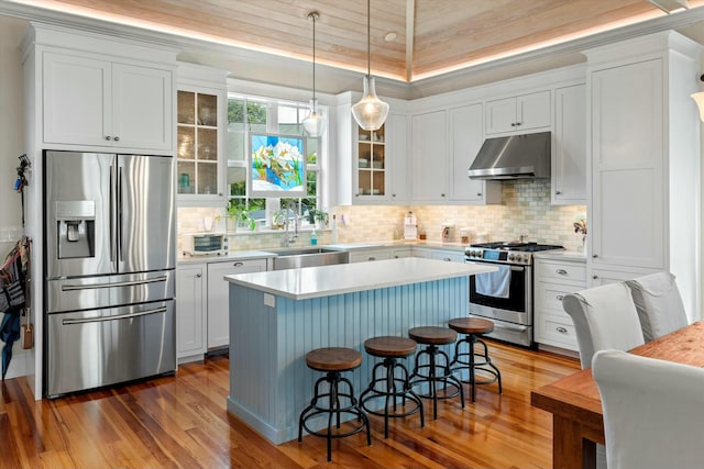 kitchen featuring a kitchen bar, sink, decorative light fixtures, a center island, and appliances with stainless steel finishes