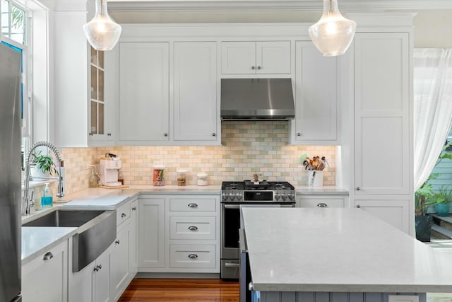 kitchen featuring white cabinetry, hanging light fixtures, stainless steel gas range, and exhaust hood