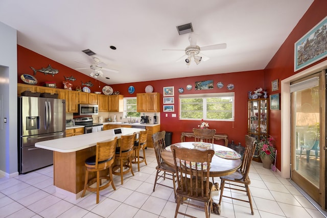 dining room with light tile patterned flooring, ceiling fan, sink, and vaulted ceiling