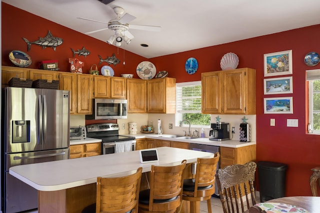 kitchen featuring sink, ceiling fan, stainless steel appliances, a kitchen breakfast bar, and light tile patterned flooring