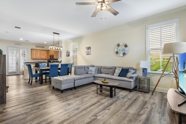 living room featuring crown molding, light hardwood / wood-style floors, and ceiling fan