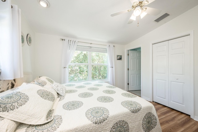 bedroom with hardwood / wood-style flooring, lofted ceiling, ceiling fan, and a closet