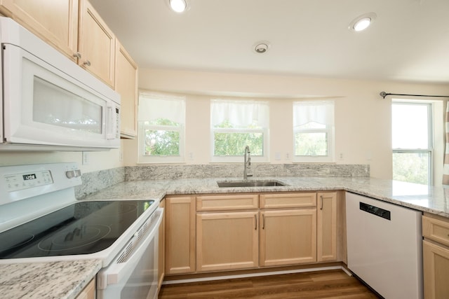 kitchen with light brown cabinetry, sink, white appliances, and kitchen peninsula