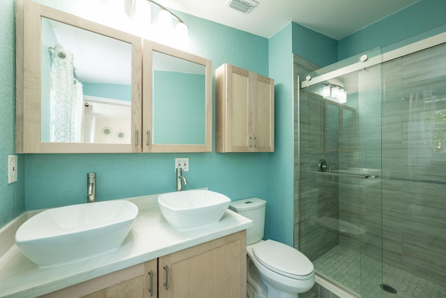 bathroom featuring toilet, vanity, and a shower with shower door