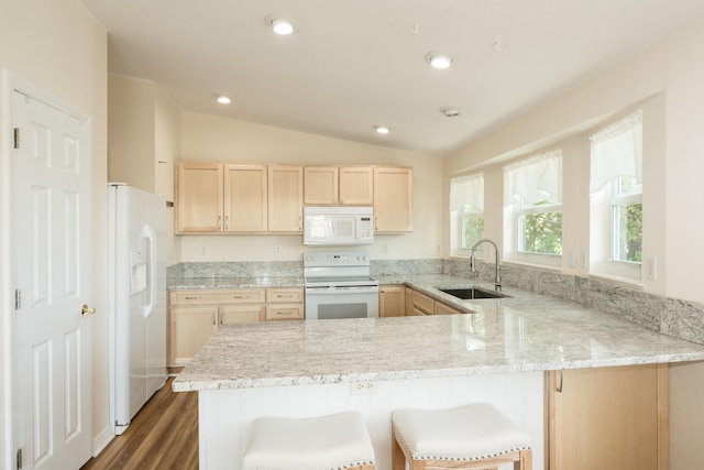 kitchen with sink, a breakfast bar area, white appliances, and kitchen peninsula