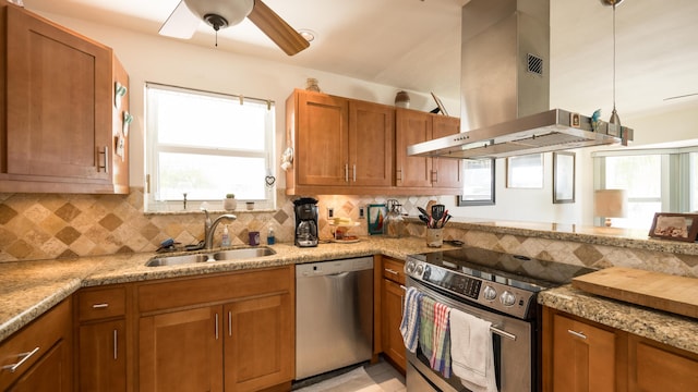 kitchen featuring sink, island range hood, stainless steel appliances, and light stone countertops