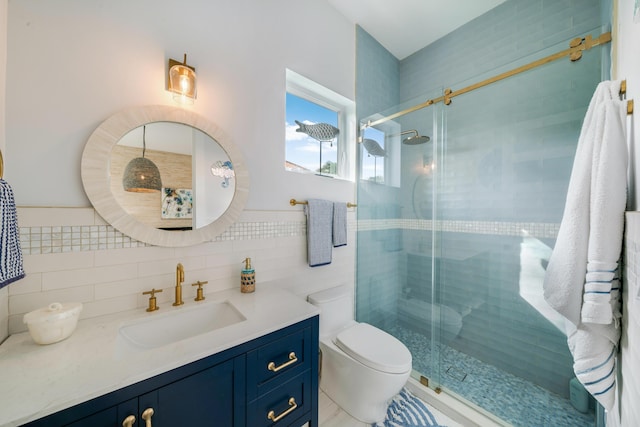 bathroom featuring vanity, toilet, a shower with shower door, and tile walls