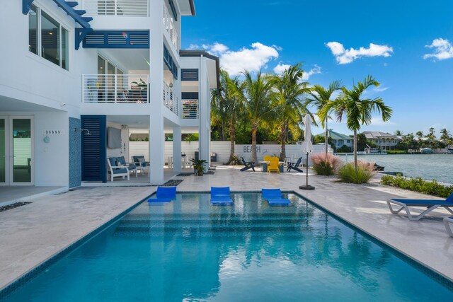 view of pool with a water view and a patio