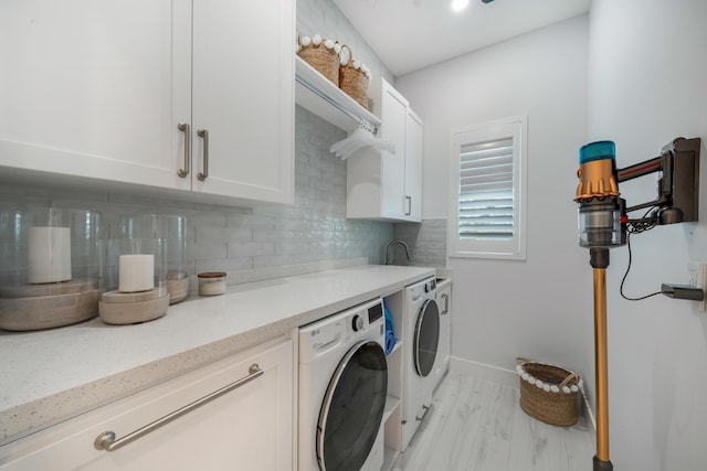 clothes washing area featuring cabinets and washing machine and clothes dryer