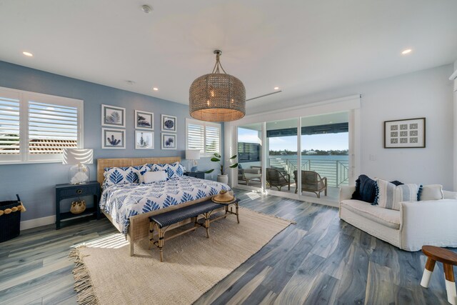 bedroom with hardwood / wood-style flooring, a water view, and access to outside